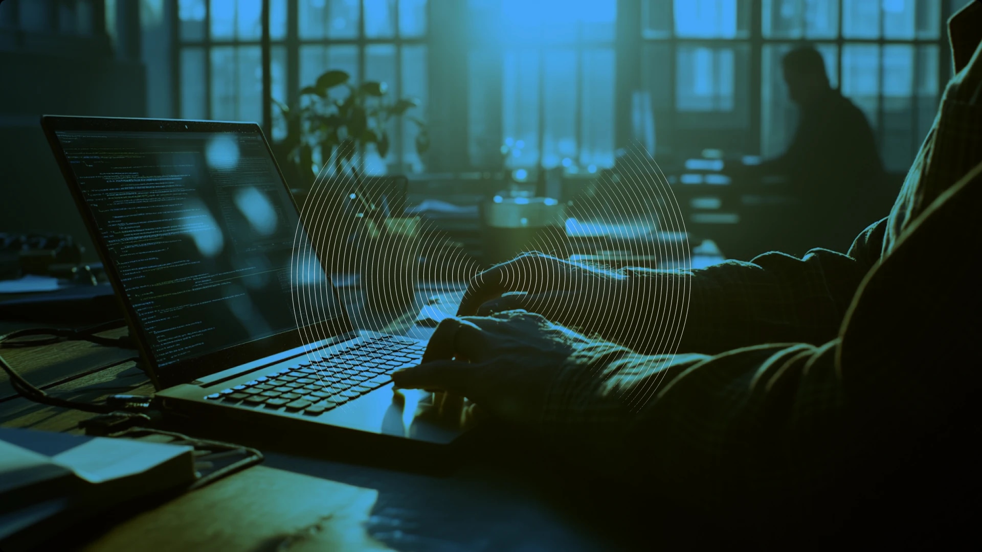 Person working on a laptop with code, in a dimly lit office environment.