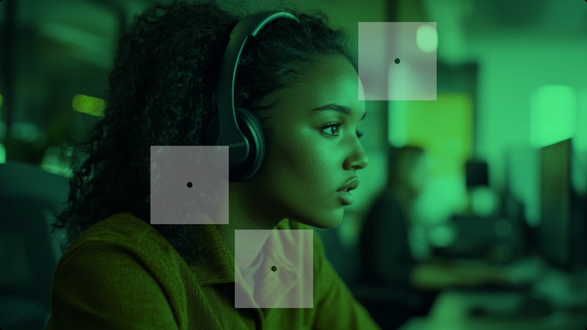 A woman wearing headphones working on a computer in a green-lit environment.