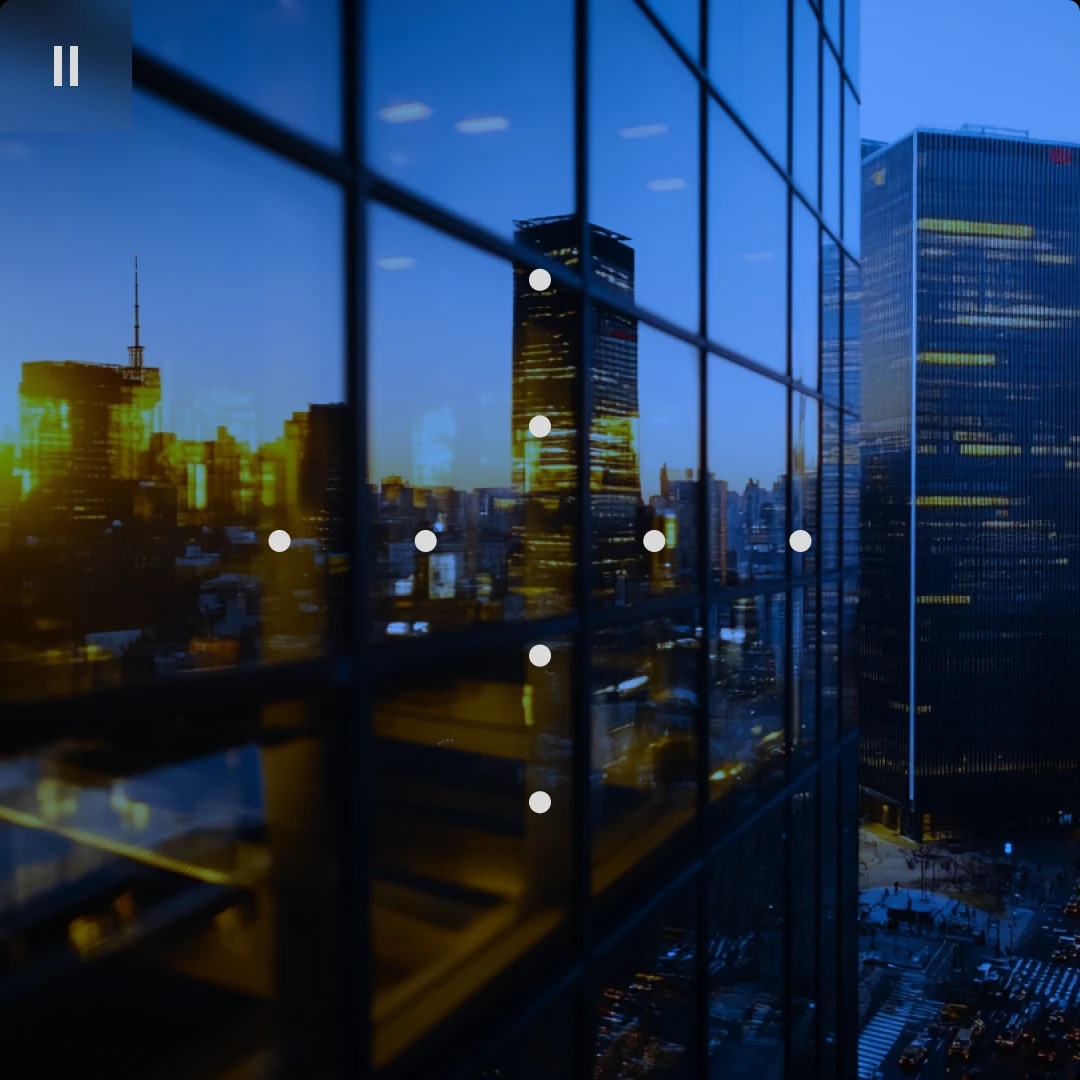 Reflection of city buildings on glass windows of a skyscraper at dusk.